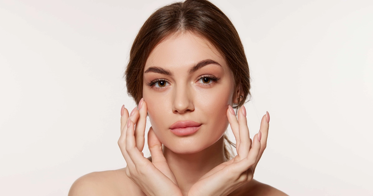 Young woman with radiant skin gently touching her face, suggesting SkinTyte Skin Tightening in Bend, OR.