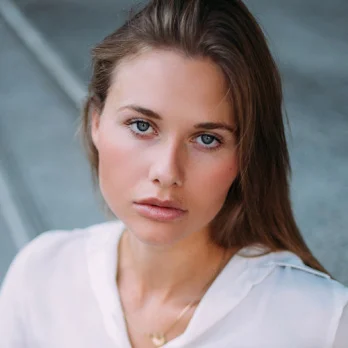 Young woman with natural makeup and clear skin showcasing facial aesthetic treatment results