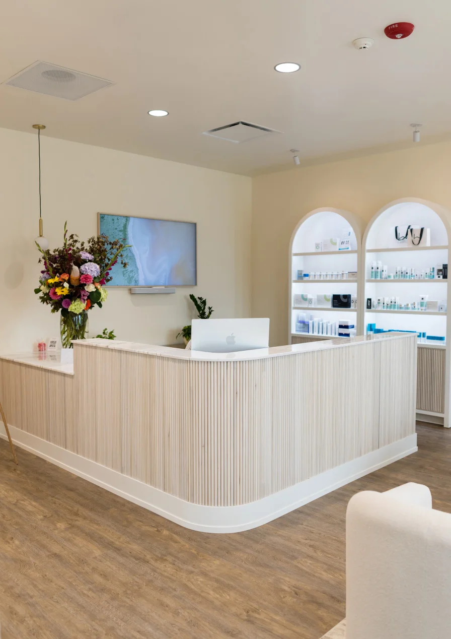 Modern white reception desk with wood paneling in bright medical office or spa waiting area