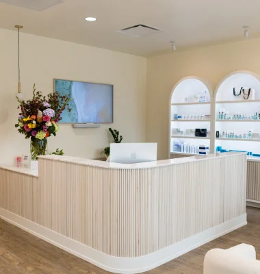 Modern medical spa reception desk with white minimalist design and natural wood accents