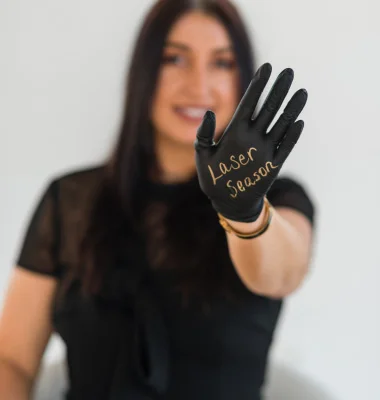 Woman in black showing black surgical glove with "Laser Genius" text written on palm