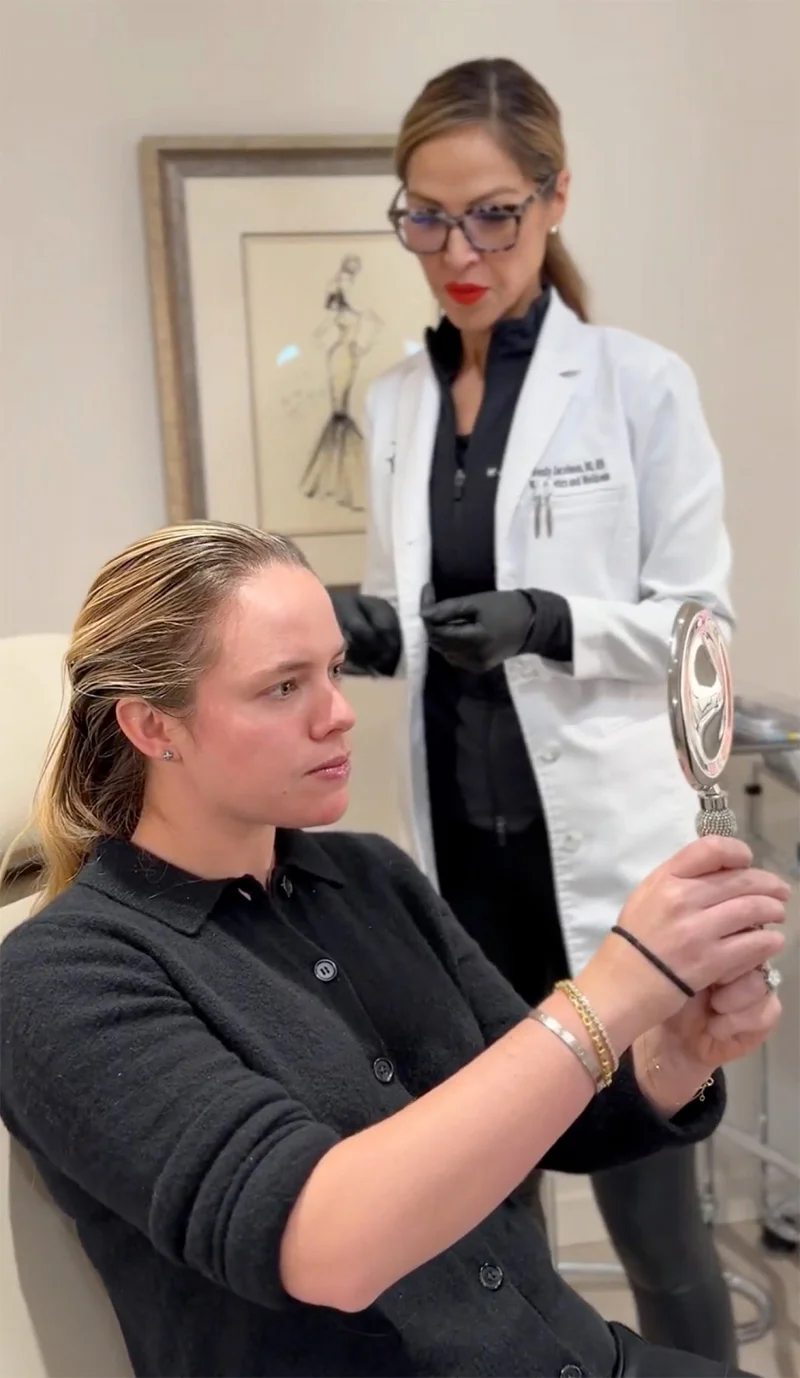 Medical professional consulting with patient holding mirror during cosmetic procedure consultation