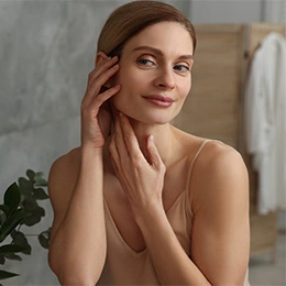 Woman with glowing skin touching face in natural light showing skincare results and healthy complexion