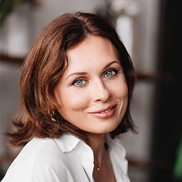Professional woman with brown hair and warm smile in white business attire headshot portrait