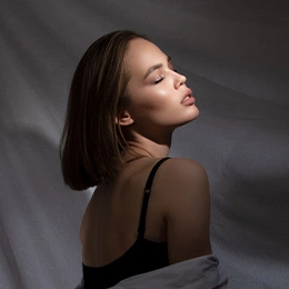 Woman in black tank top with eyes closed in elegant side profile portrait with dramatic lighting