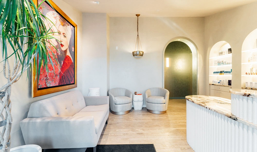 Modern white reception area with gray sofa, arched doorway, and colorful wall art in bright office space - in Bend, OR
